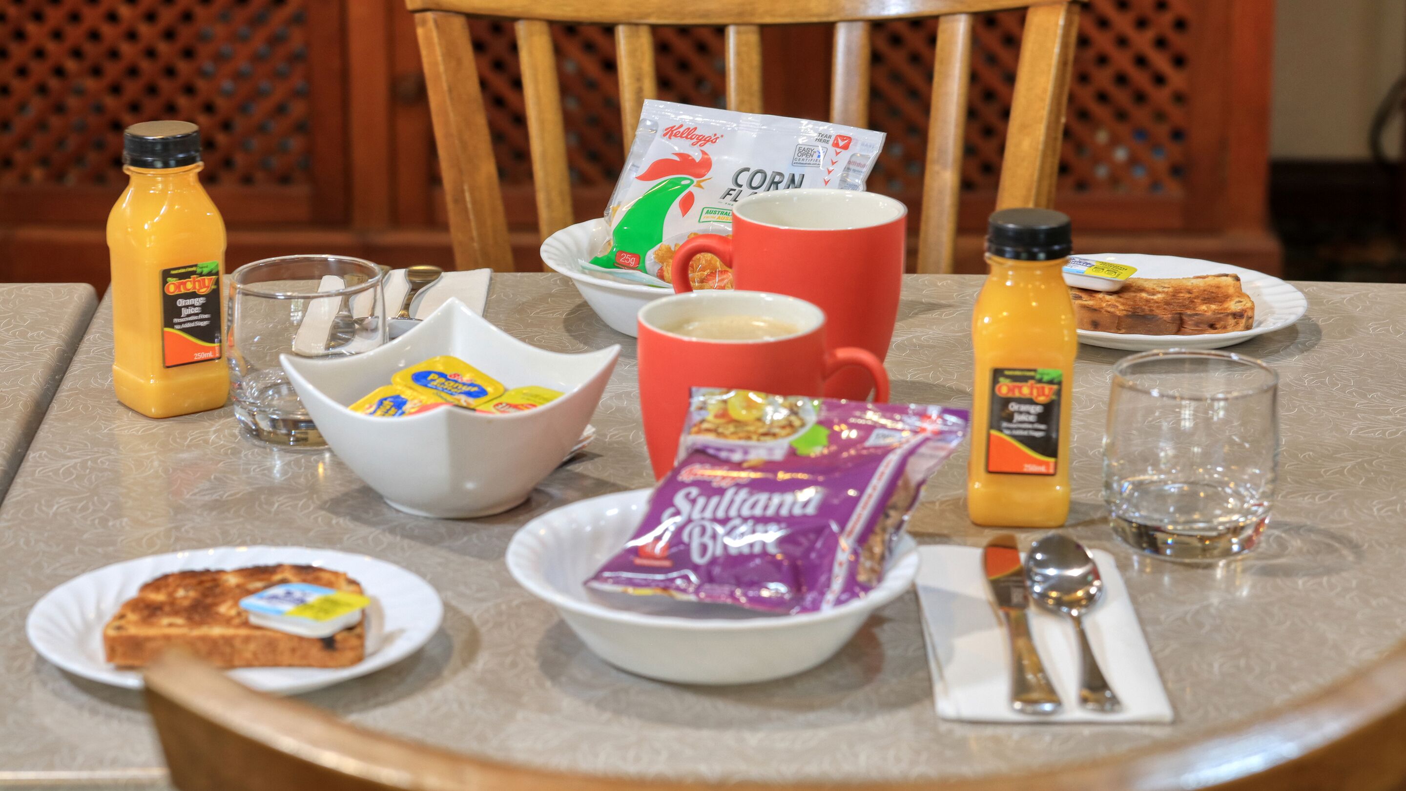 A breakfast table with various food items, including toast, cereal, and juice.