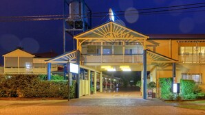 A hotel with a covered entrance, multiple balconies, and a well-lit facade.