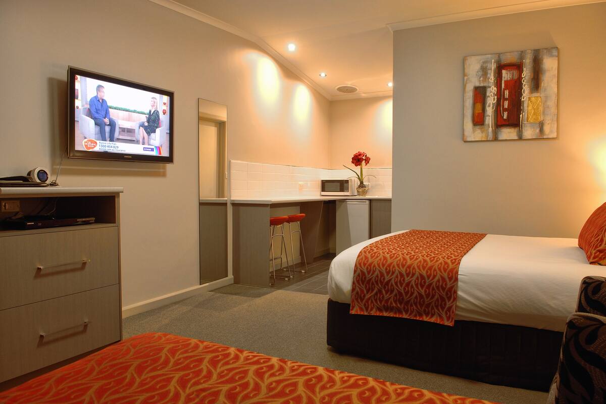 A hotel room with a TV, a bed, a desk, and a microwave.
