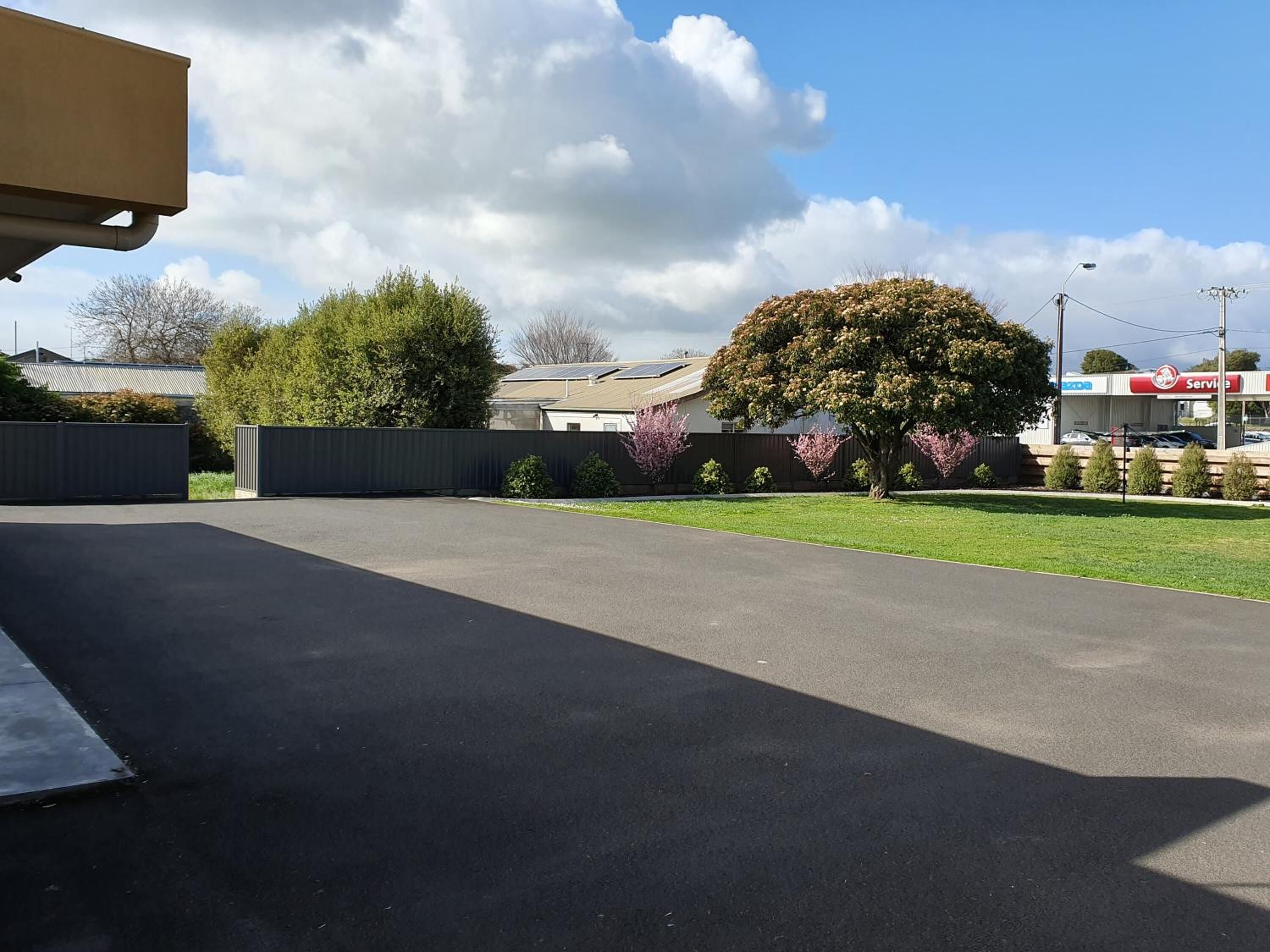 A parking lot with a paved surface, a fenced area, and a building with a solar panel roof.
