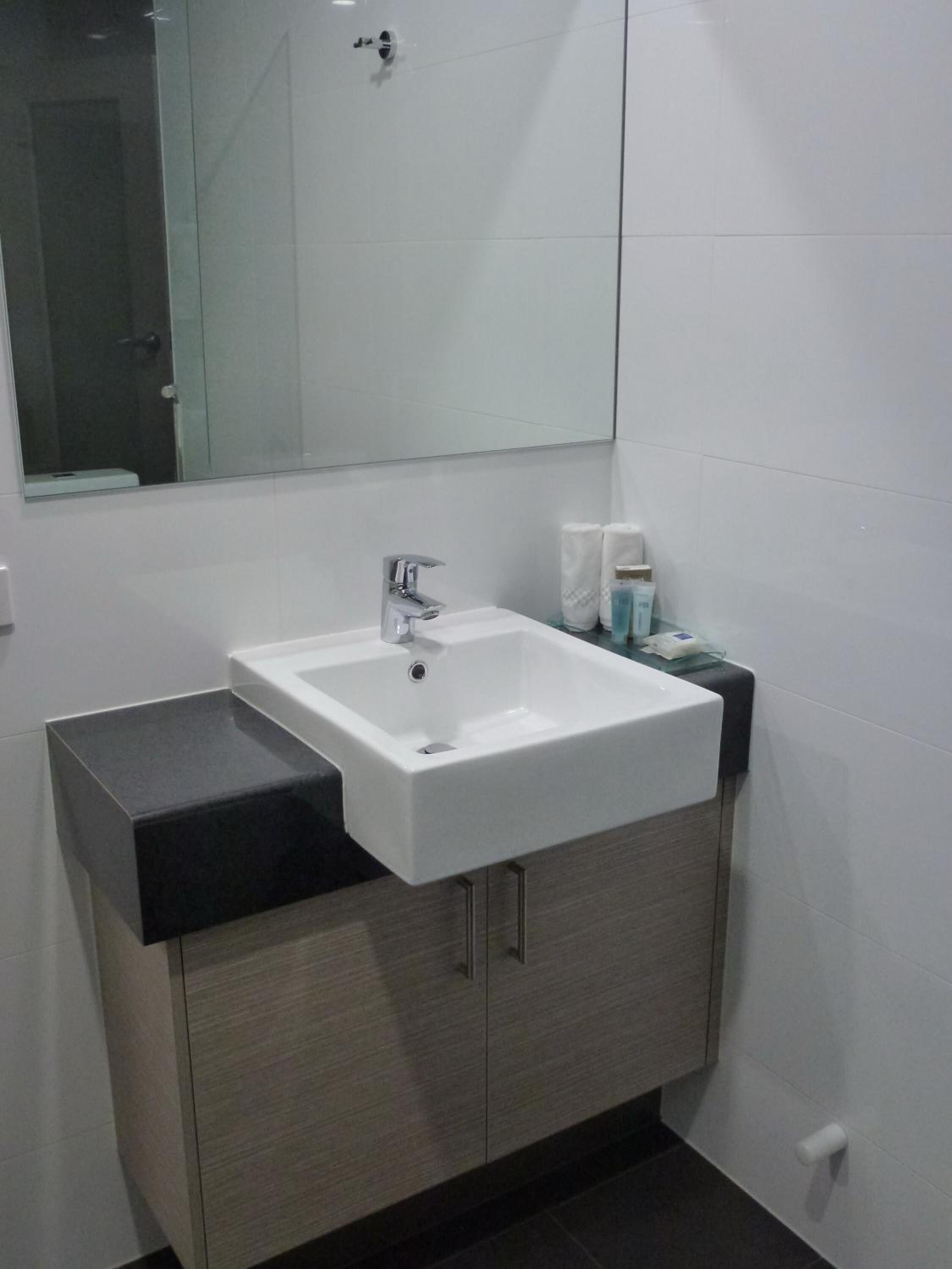 Une salle de bain moderne avec un lavabo blanc, un plan de travail noir et des meubles en bois.