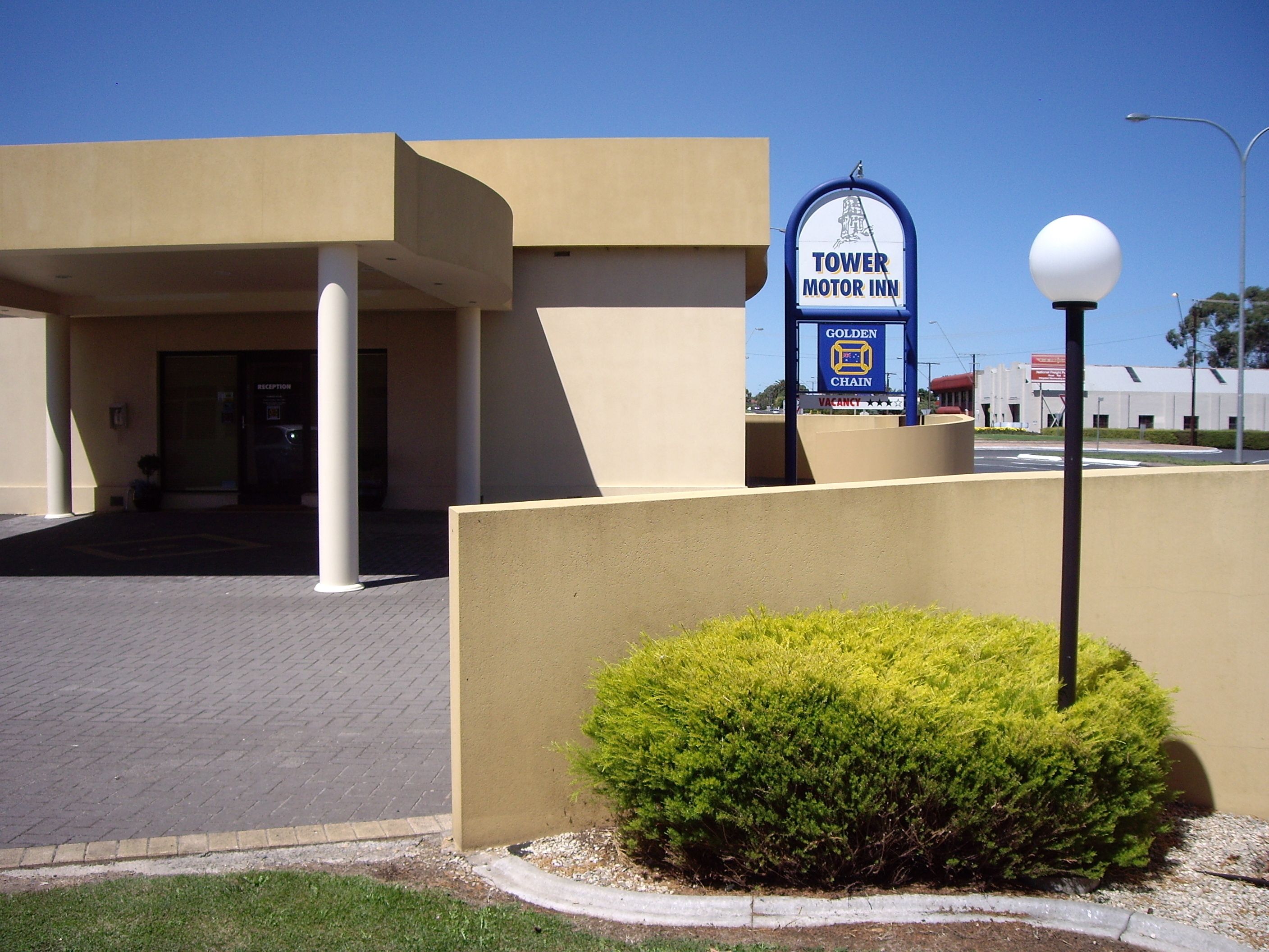 Un edificio moderno con un cartel que indica Tower Motor Inn y Golden Chain.