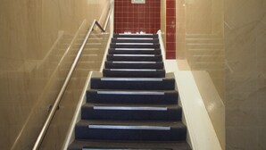 Eine Treppe mit Handlauf, die zu einer roten Tür mit Schild für Nichtraucher führt.