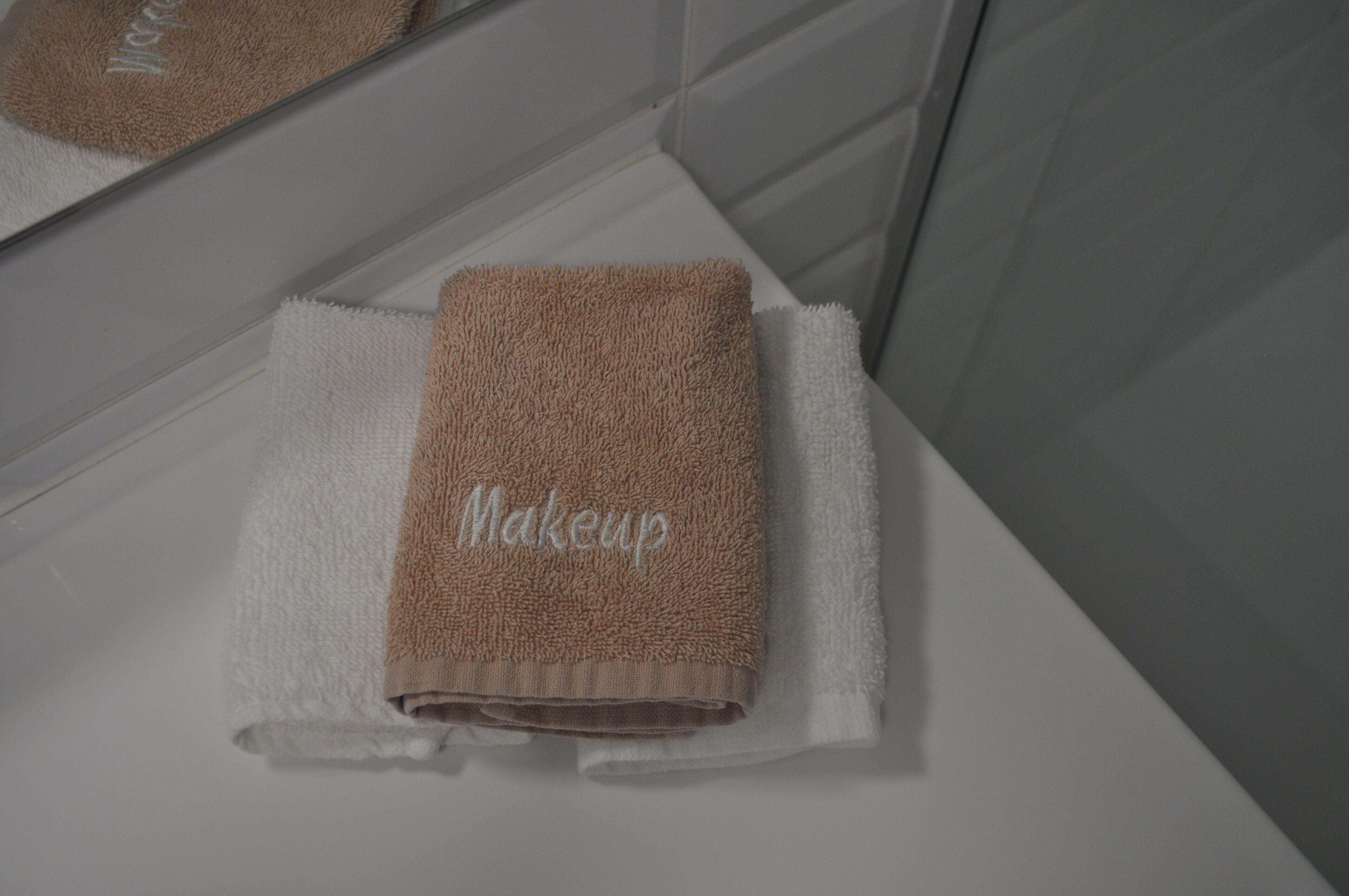 A bathroom with a white sink, a towel, and a mirror.