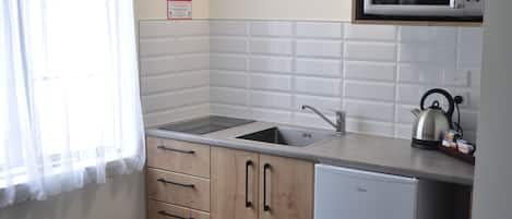 A compact kitchen with a sink, a microwave, and a kettle.