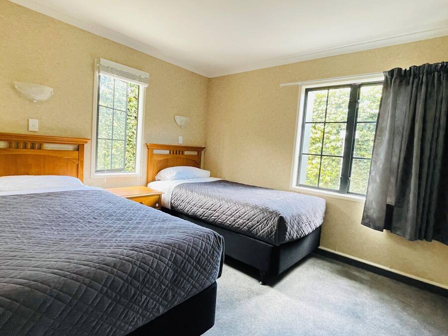 A hotel room with two beds, a window with curtains, and a wooden headboard.