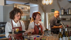 A kitchen with chefs preparing food, a wine rack with bottles, and an exit sign. - Wharepuke Subtropical Accommodation (Kerikeri)