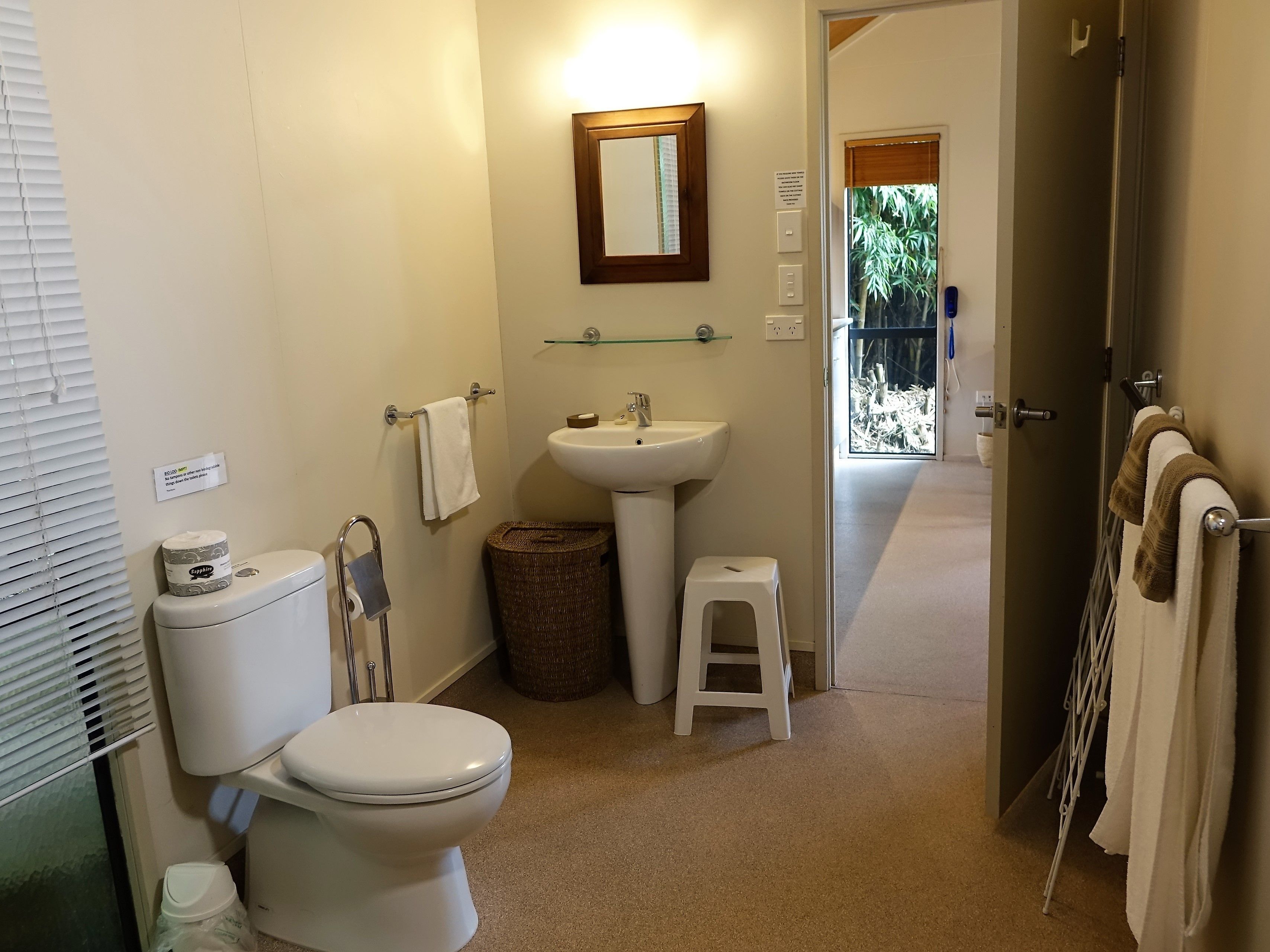 A compact bathroom with a toilet, sink, and a small stool.