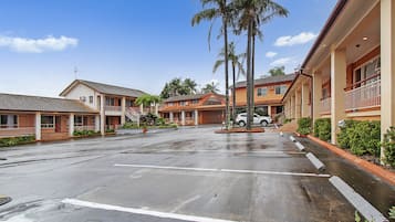 A hotel with a parking lot, multiple buildings, and palm trees.