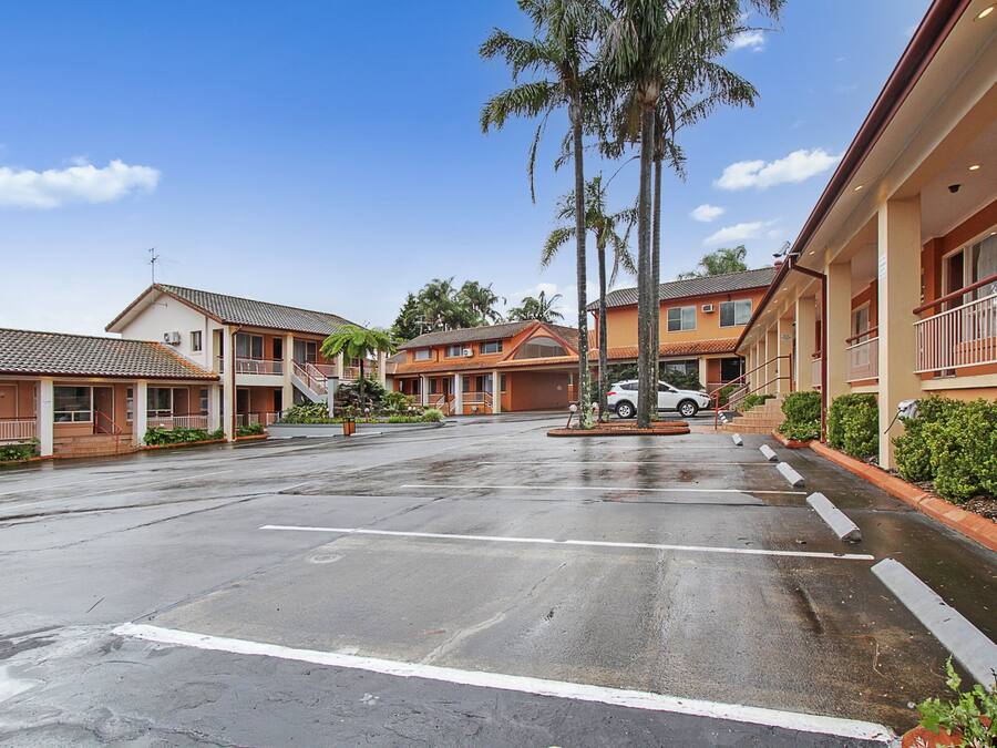 A hotel with a parking lot, multiple buildings, and palm trees.