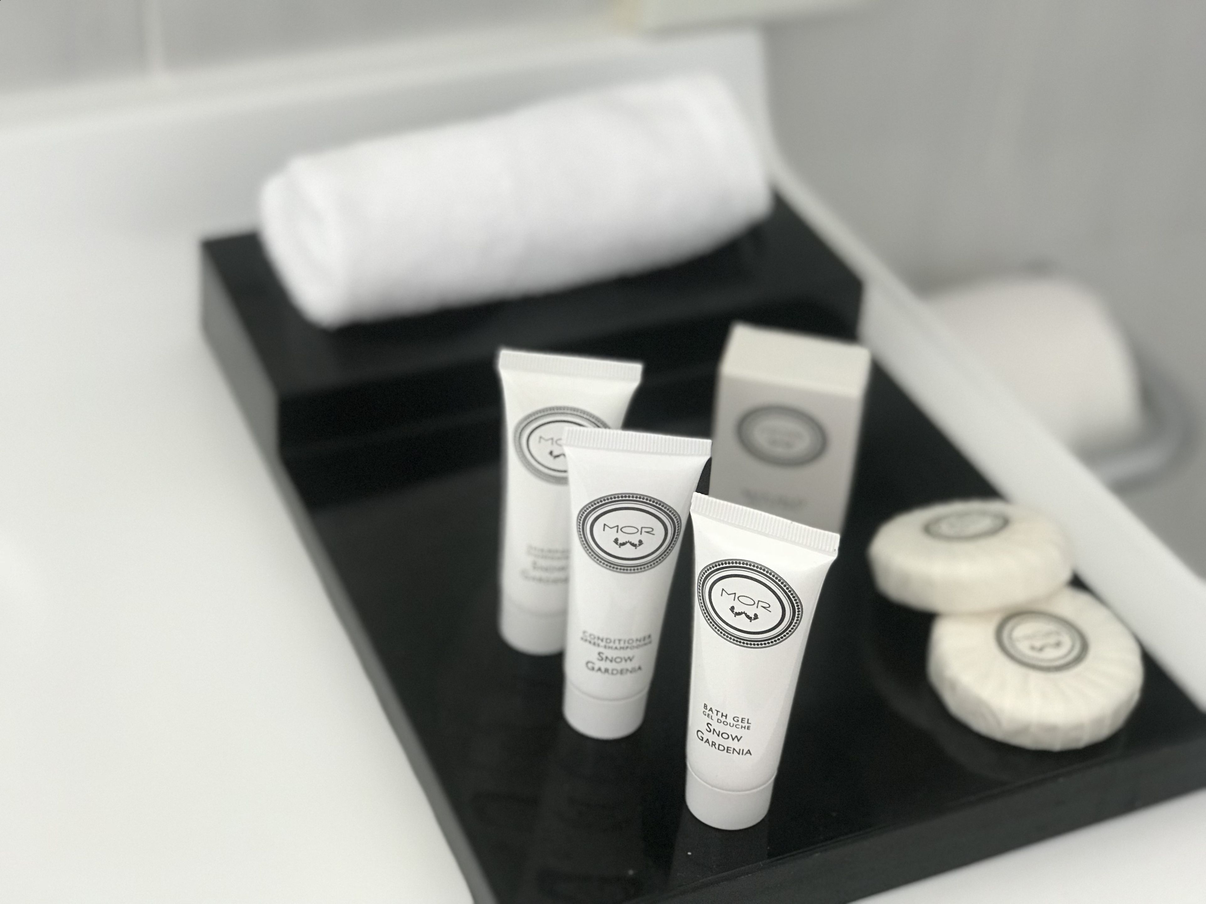 A tray with toiletries including a towel, bath gel, and other personal care items.