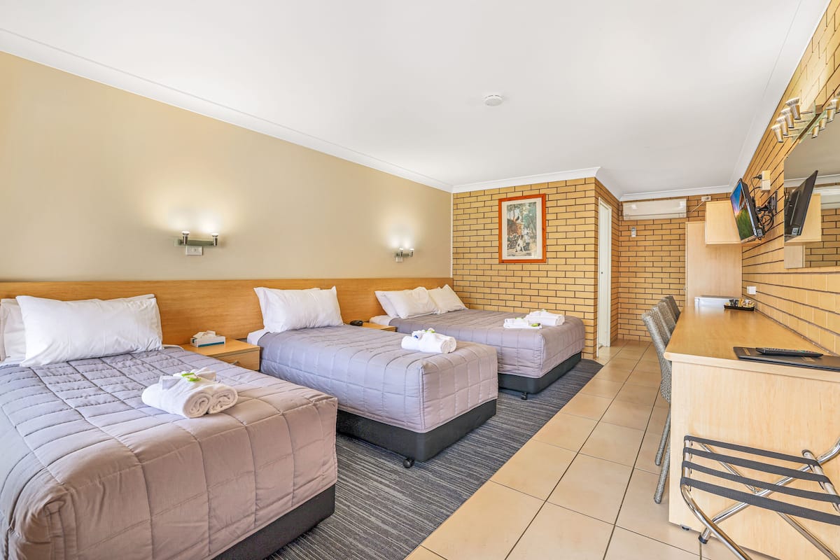 A hotel room with two beds, a desk, and a small kitchenette.