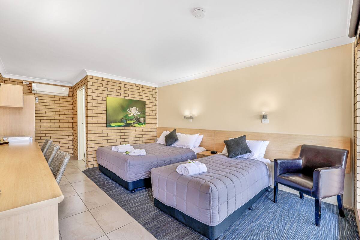 A hotel room with two beds, a desk, and a chair.