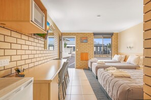 A modern hotel room with a kitchen area, a balcony, and a large bed with towels. - The Stagecoach Inn Motel (East Tamworth)