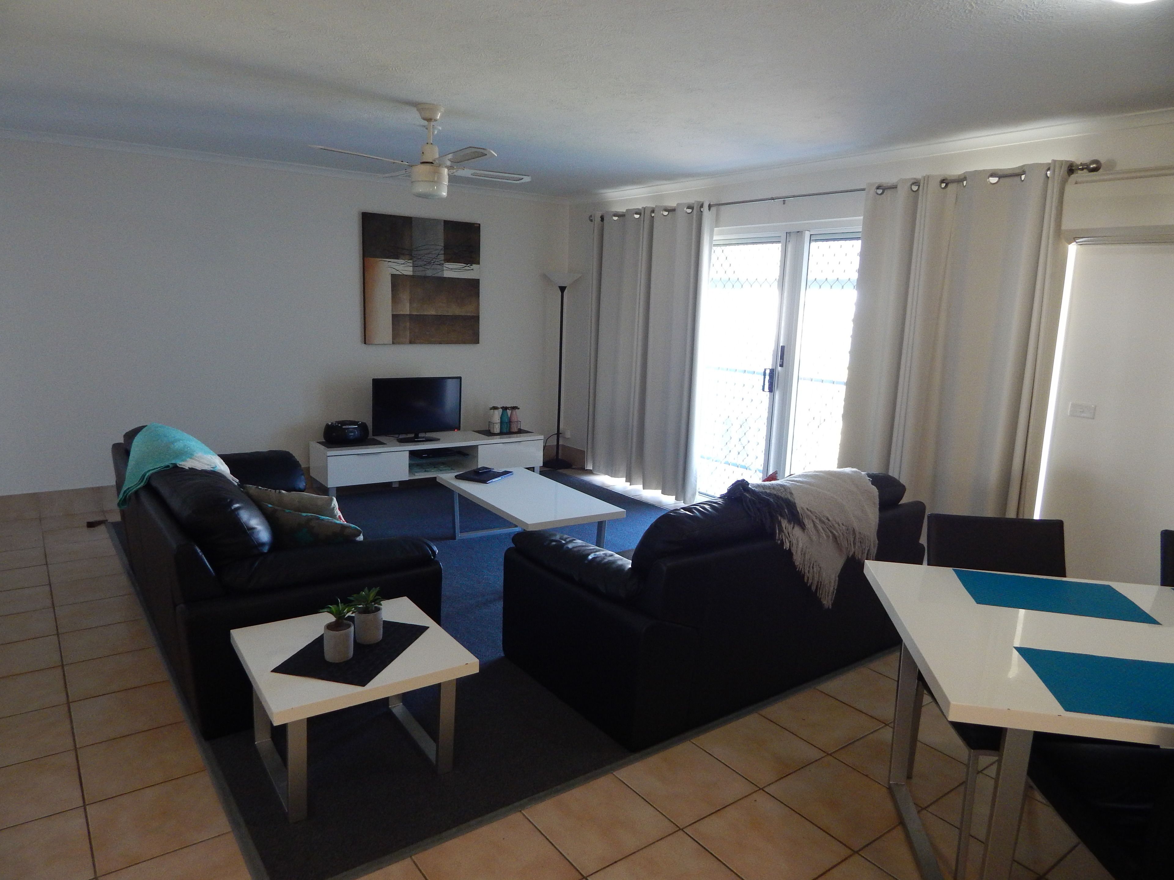 Un salon avec un canapé, une table basse, un téléviseur et un ventilateur de plafond.
