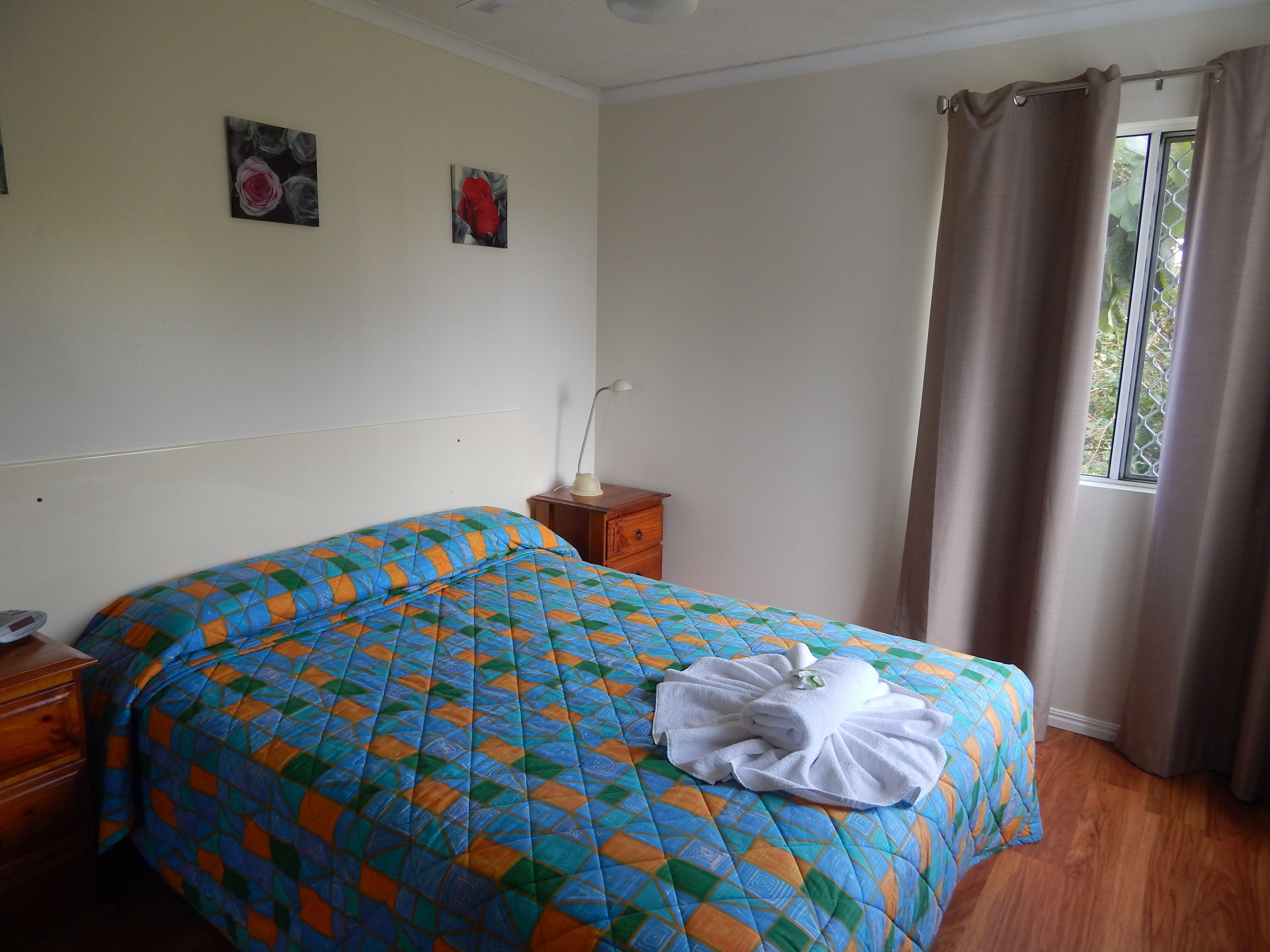 A hotel room with a bed, a nightstand, a lamp, and a window with curtains.