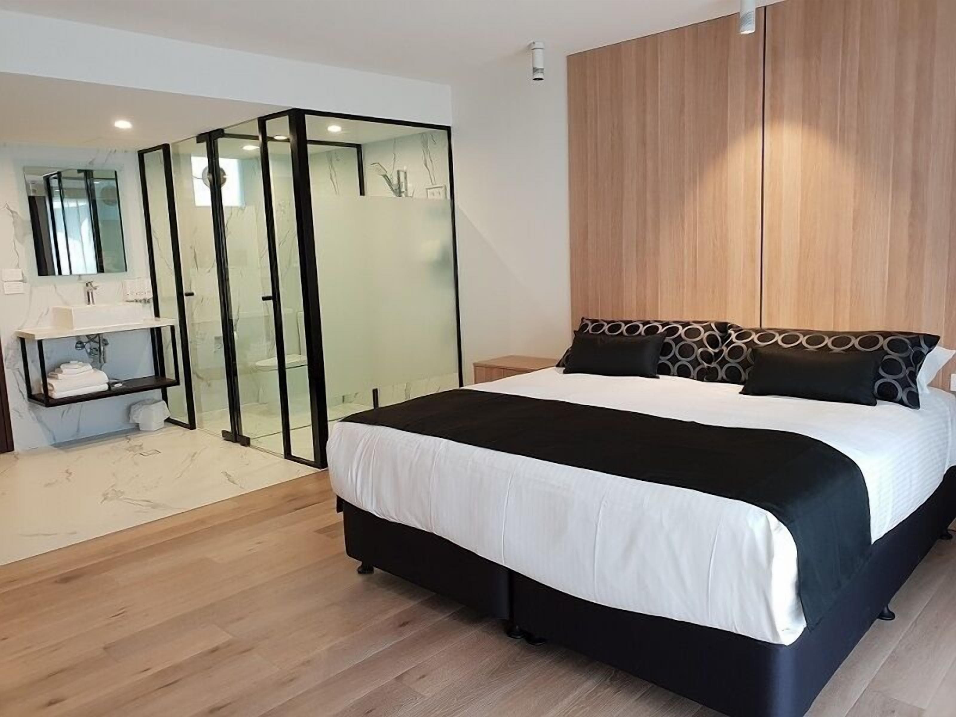 Quarto moderno com cama grande, closet espaçoso e banheiro com chuveiro de vidro.