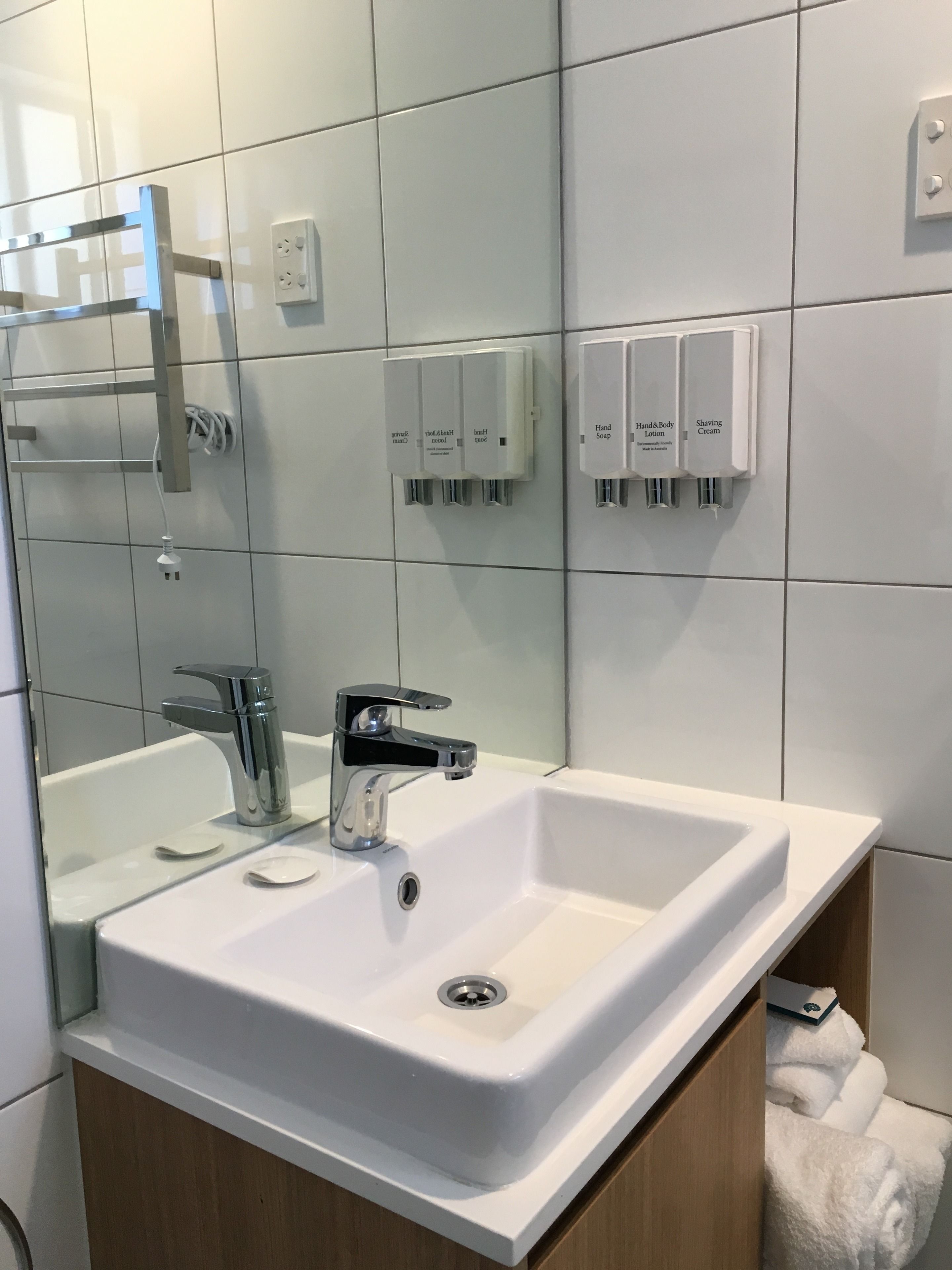 Un bagno moderno con lavandino bianco, rubinetteria cromata e dispenser di sapone integrati.