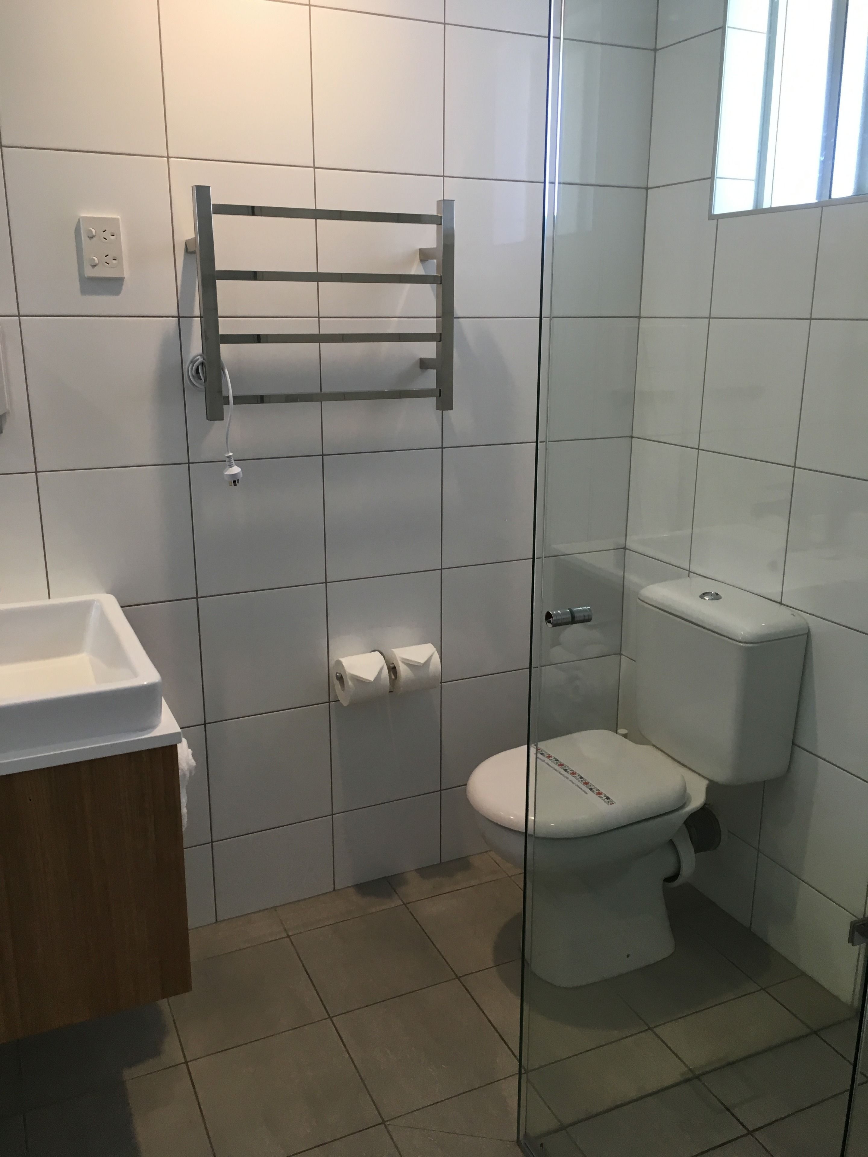 A bathroom with a toilet, a sink, and a glass shower enclosure.