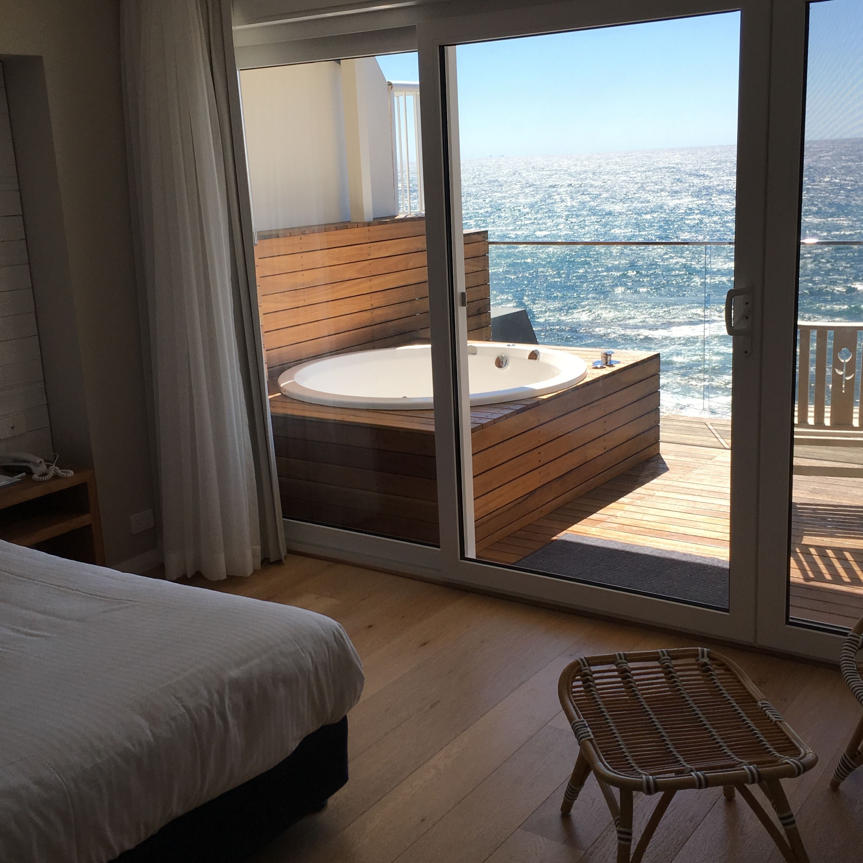 A room with a large bed, a wooden bathtub, and a view of the ocean.