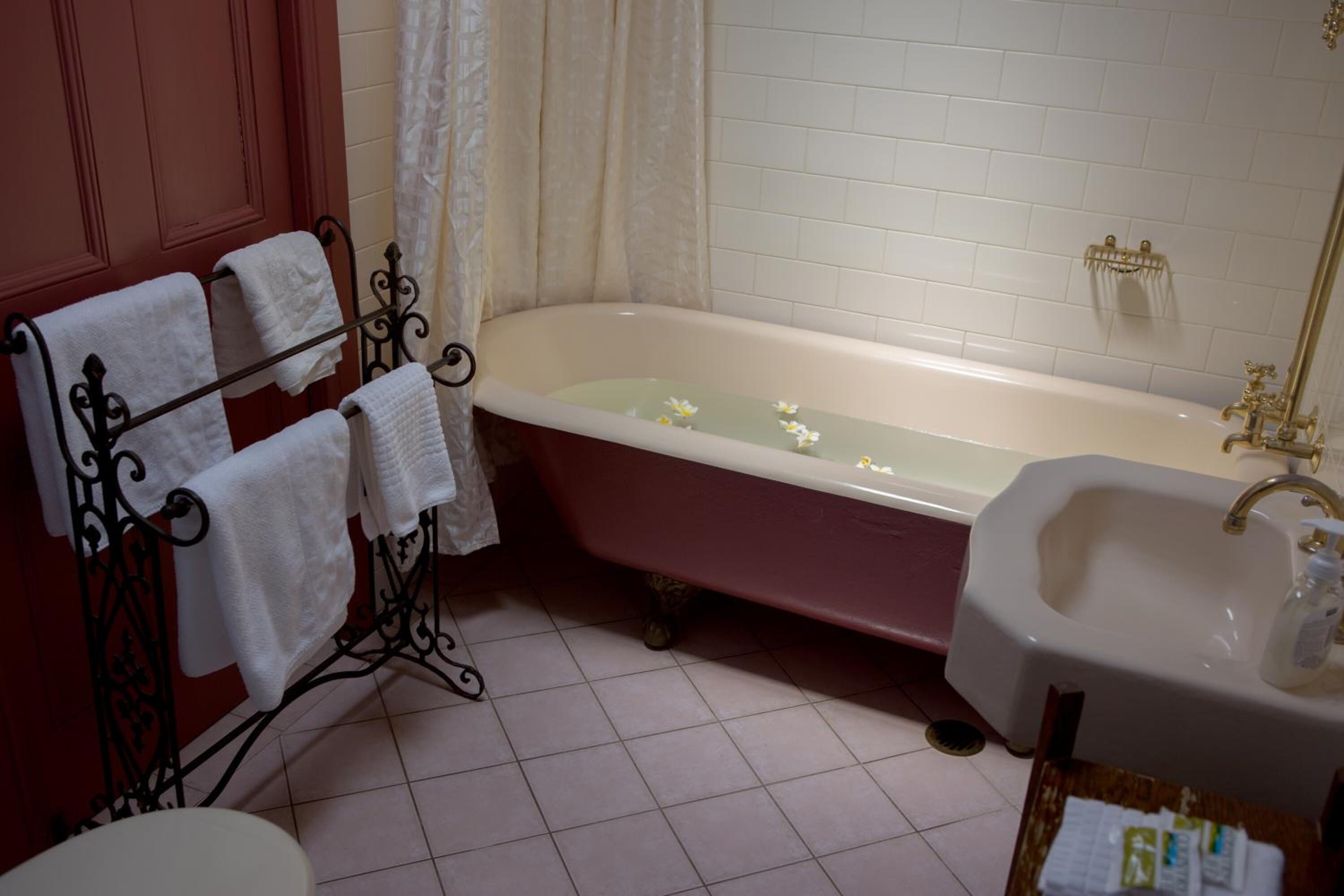 A bathroom with a freestanding bathtub, a sink, and a towel rack with multiple towels.