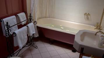 A bathroom with a freestanding bathtub, a sink, and a towel rack with multiple towels.
