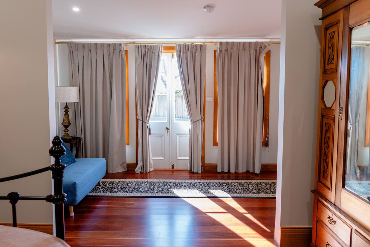 A hotel room with a bed, a wooden cabinet, and a view through the curtains.