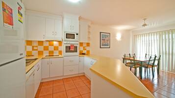 A kitchen with white cabinets, a microwave, and a dining area with a table and chairs.