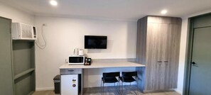 A compact kitchenette with a microwave, a small refrigerator, a sink, and a flat-screen TV mounted on the wall. - Y Motels Gympie (Monkland)