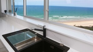 A kitchen with a modern sink and a large window overlooking the ocean. - Narrowneck Court (Surfers Paradise)