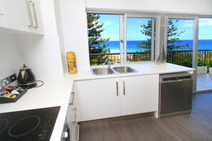 A modern kitchen with a large window offering a view of the ocean.