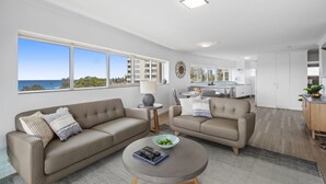 A modern living room with two sofas, a coffee table, and a view of the city. - Narrowneck Court (Surfers Paradise)