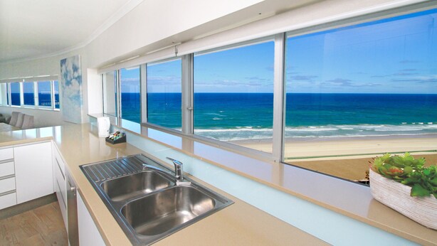 A modern kitchen with a large window overlooking a beach. - Narrowneck Court (Surfers Paradise)