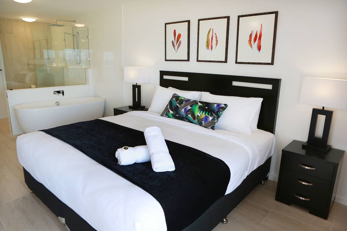 Una habitación de hotel moderna con una cama grande, baño privado y obras de arte en la pared.