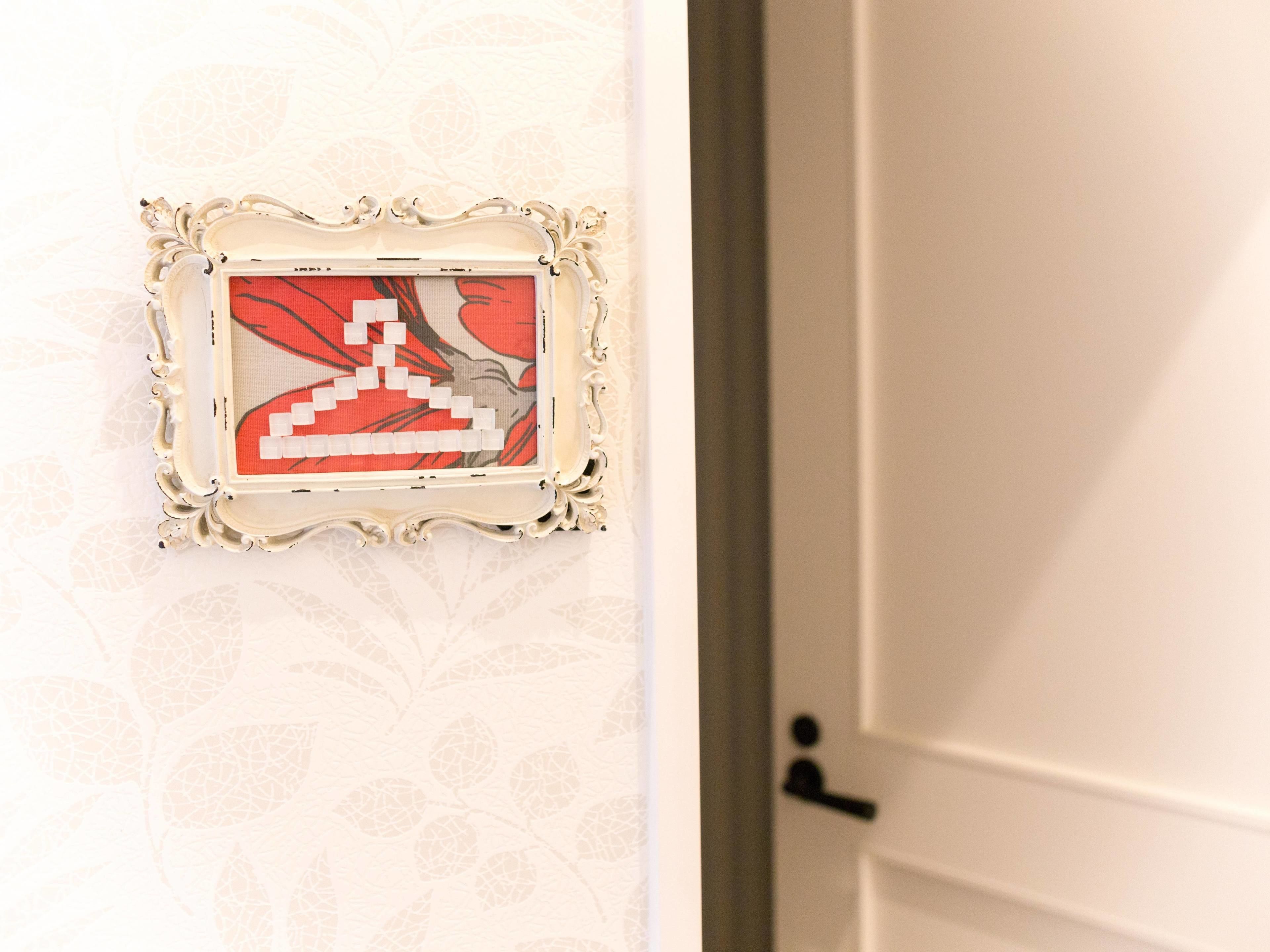 Una obra de arte enmarcada en una pared, con una puerta a la derecha.