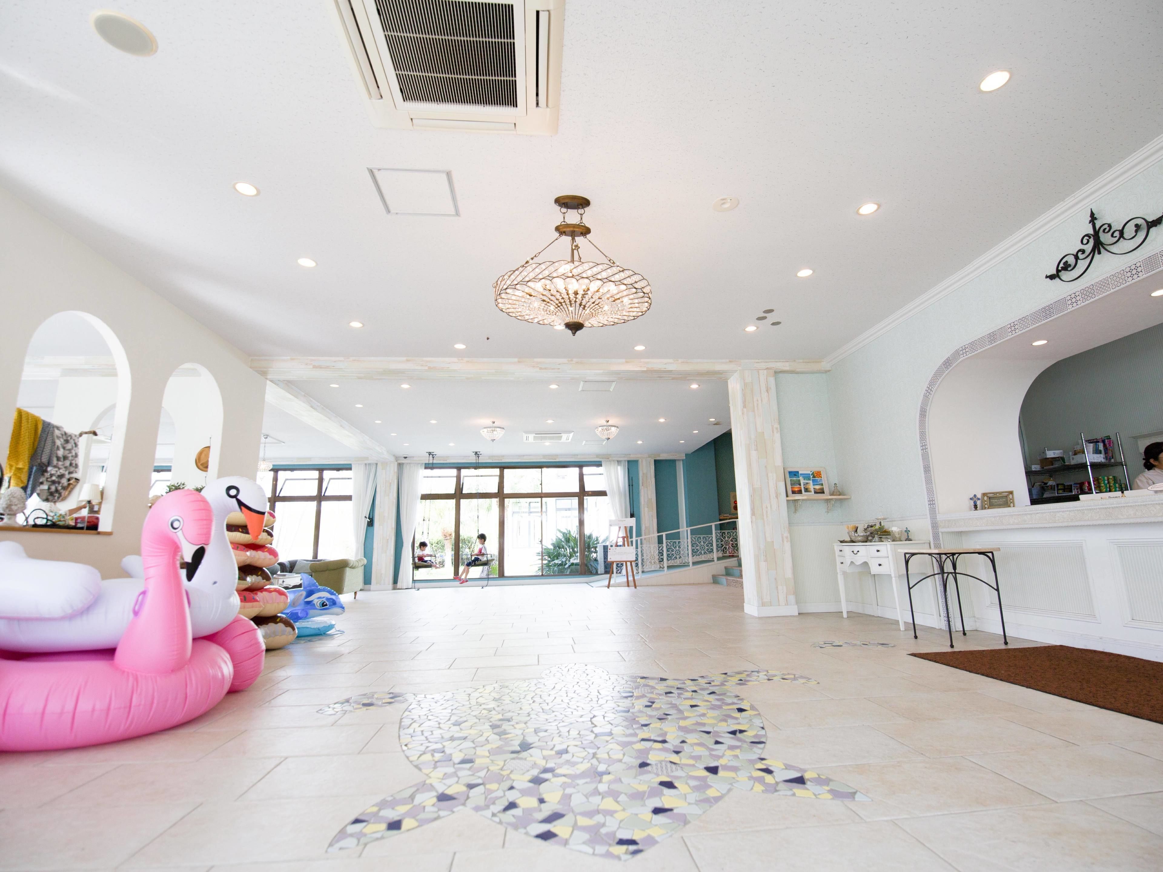 Un hall d’entrée spacieux, doté d’un sol carrelé, d’un grand lustre et d’une décoration représentant un flamant rose.