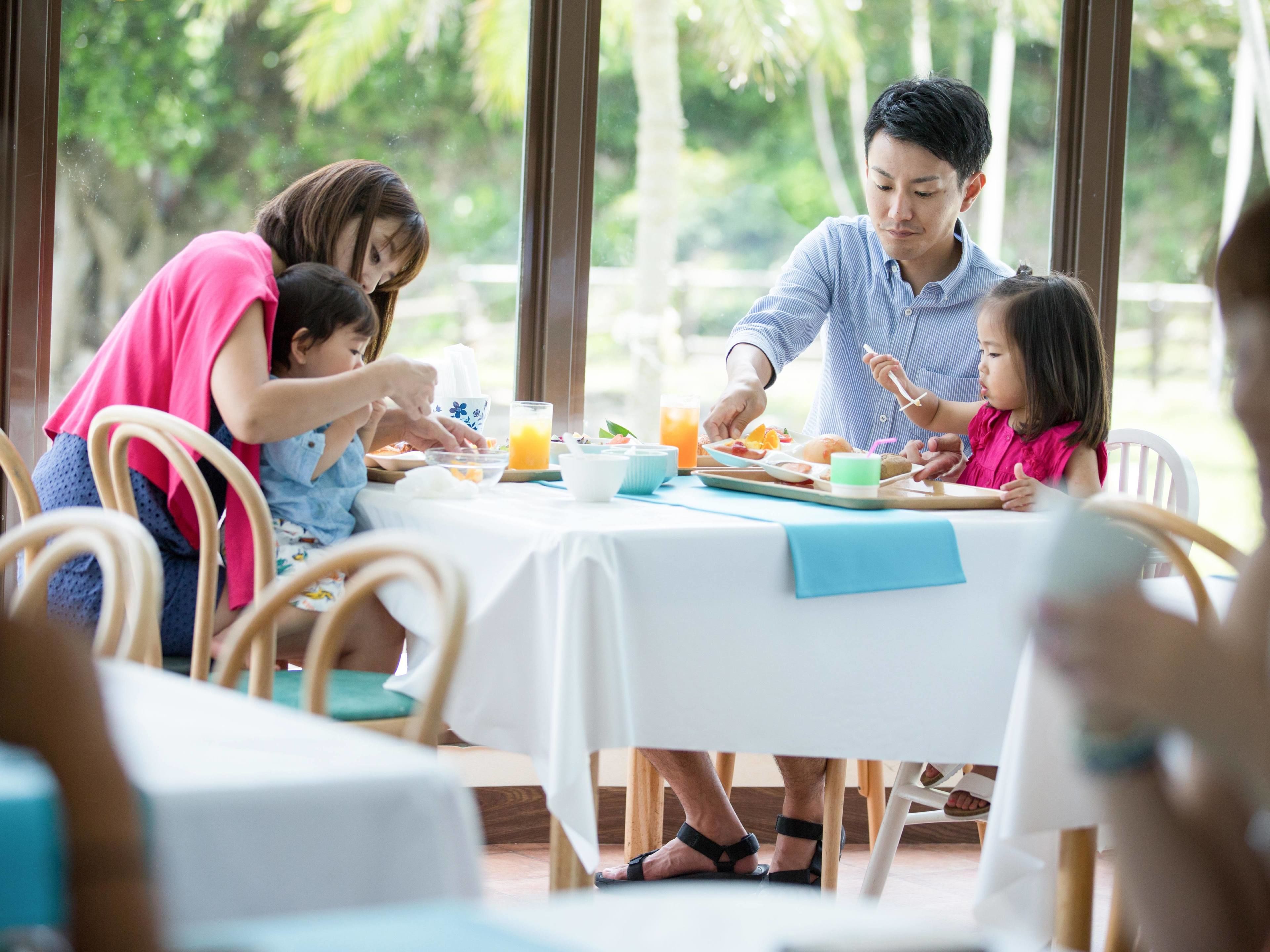 A family dining at a table with a view of greenery outside.
