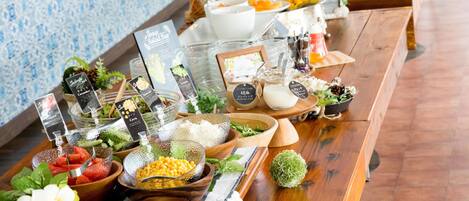 A buffet table with various food items and condiments, including fresh fruits, vegetables, and dairy products.