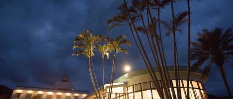 A hotel with a circular building, palm trees, and a pool area.