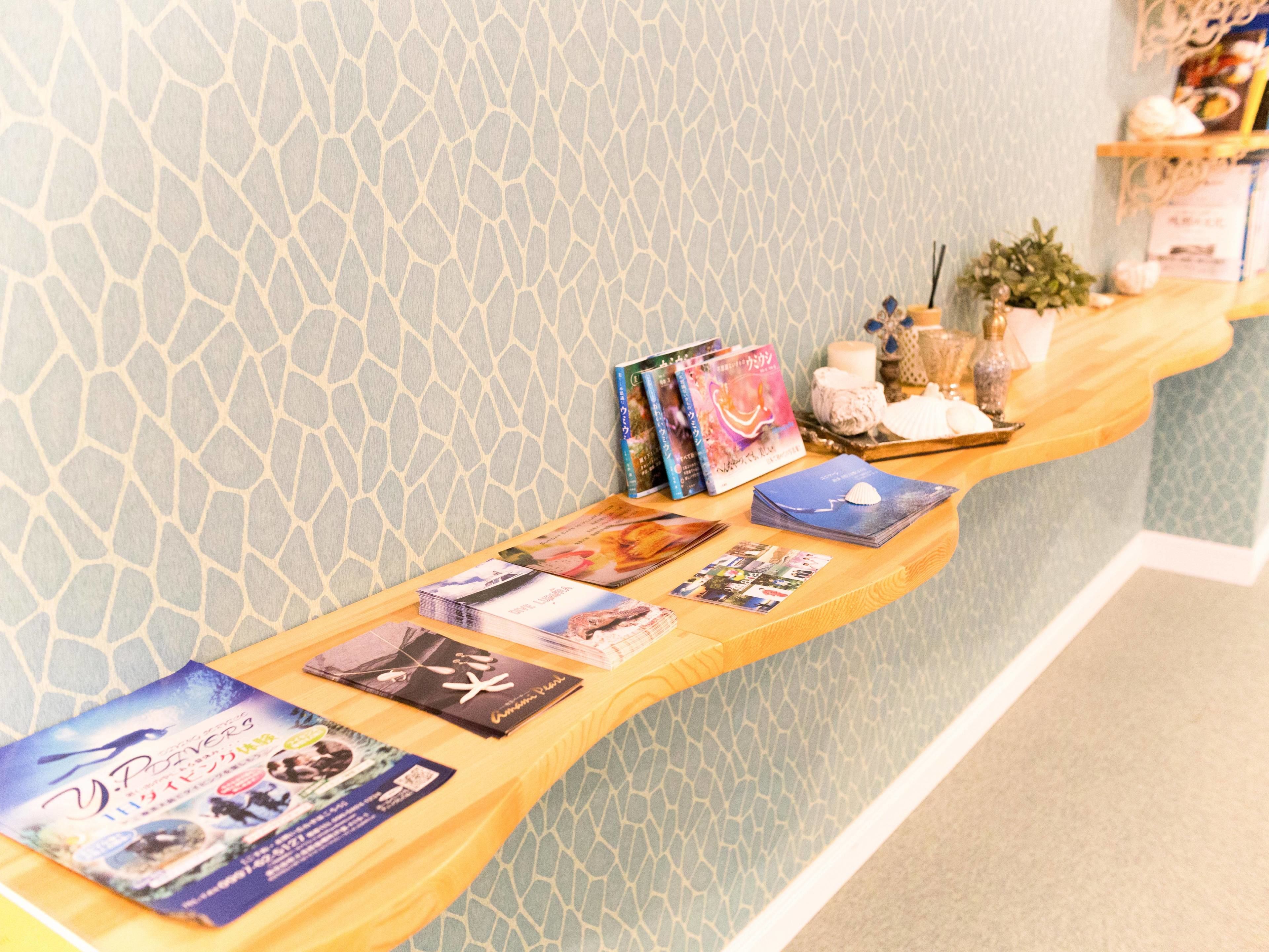 A reception desk with a patterned wall, a wooden counter, and various items including books, a small plant, and decorative objects.