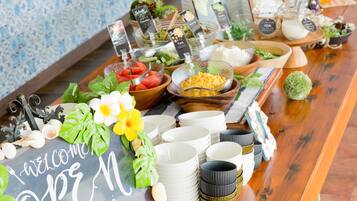 Una mesa de buffet con diferentes alimentos, platos y un cartel de bienvenida.