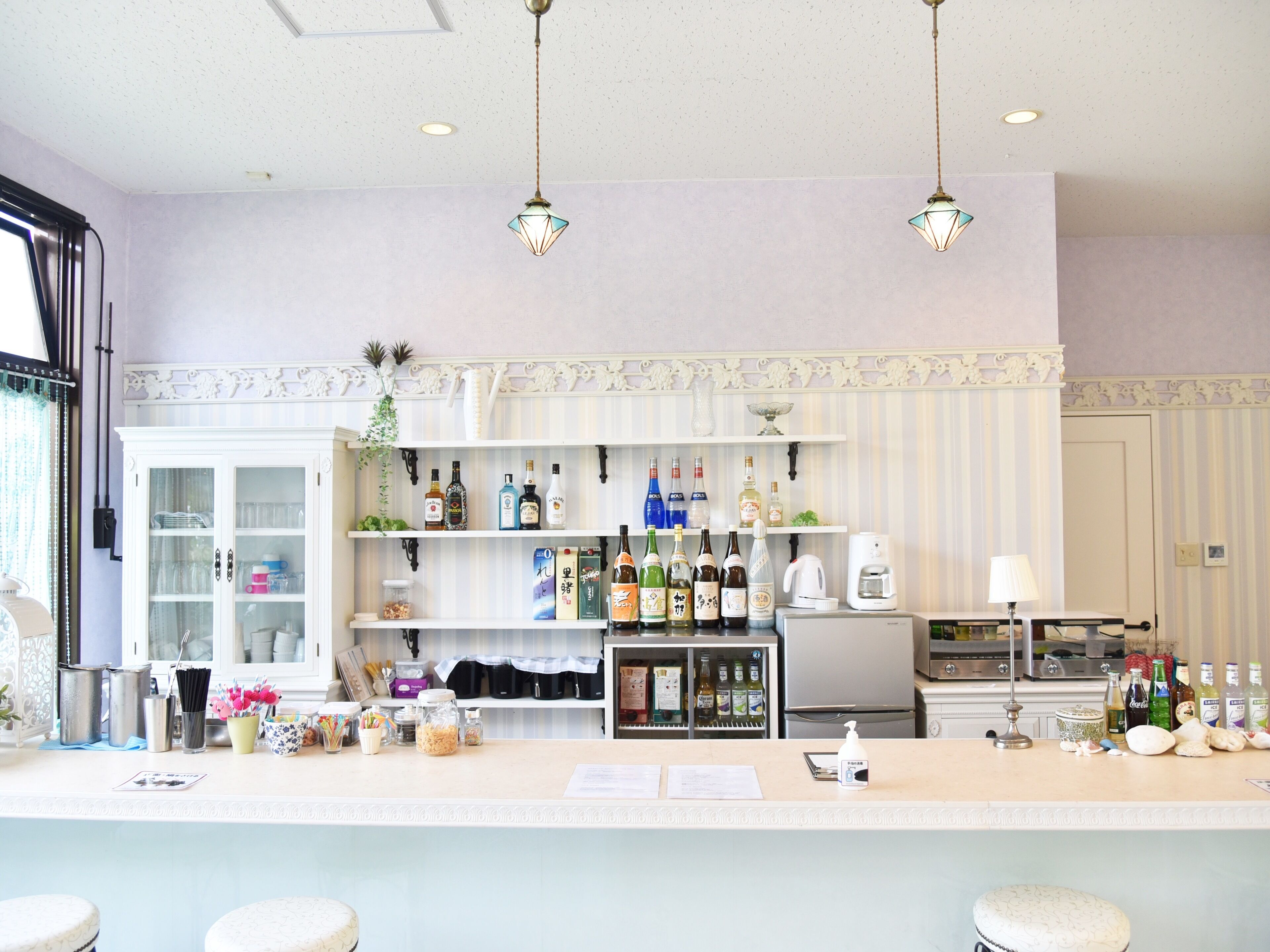 A bar area with shelves of liquor bottles, a refrigerator, and a coffee machine.