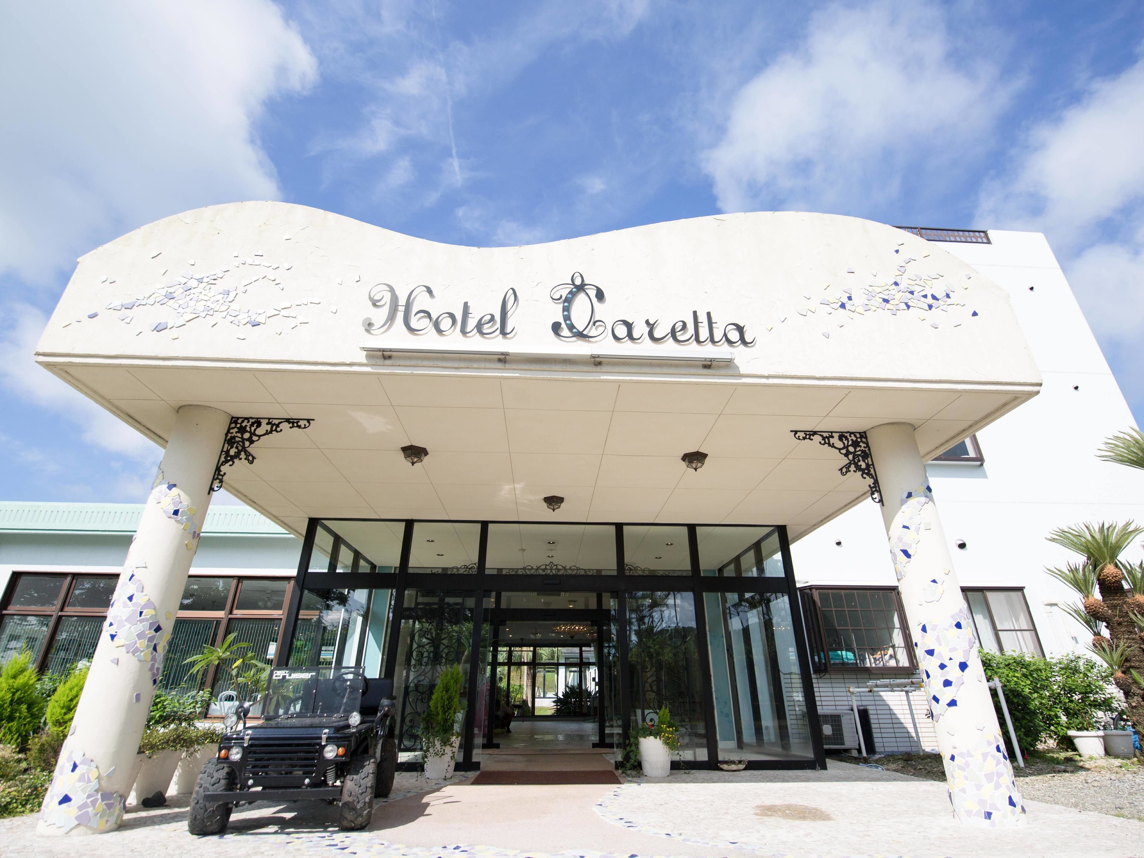 Hotel Caretta con una entrada moderna, amplias puertas de vidrio y un pasillo cubierto.