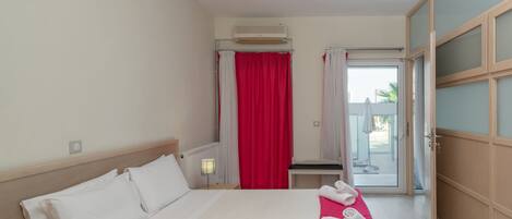 A hotel room with a bed, a desk, a chair, and a view of the outside.