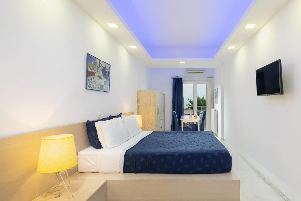 Une chambre d’hôtel moderne équipée d’un lit, d’une table de chevet, d’une lampe et d’un téléviseur fixé au mur.