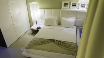 A neatly arranged hotel room with a bed, bedside table, lamp, and framed pictures on the wall.