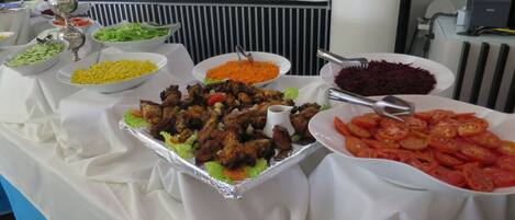 Ein Buffet mit verschiedenen Speisen, darunter Salate, Fleisch und Reis.