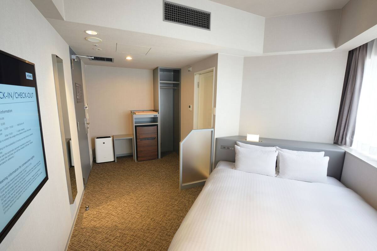 Une chambre d’hôtel équipée d’un lit, d’un bureau, d’une armoire et d’une petite kitchenette.