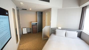 A hotel room with a bed, a desk, a wardrobe, and a small kitchenette.