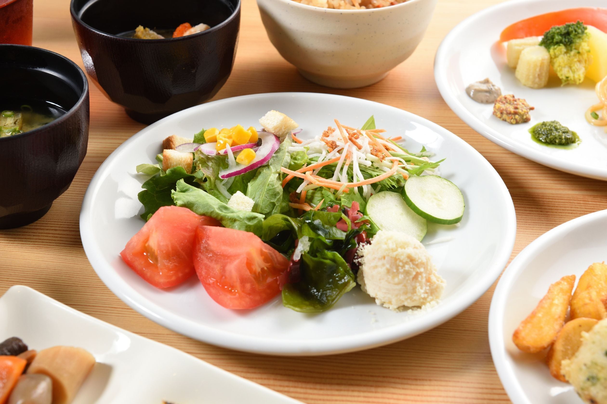 A dining table with various dishes including a salad, vegetables, and bread.